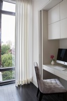 Modern home office with storage cabinets and tall windows with city view.