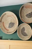 Display of woven plates on green bedroom wall - detail 