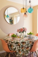 Orange chairs around small dining table with retro tablecloth
