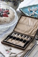 Box of antique silver forks on country dining table - detail