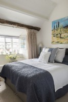 Colourful artwork over bed in country bedroom