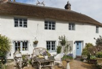 Exterior of thatched country cottage with rustic garden furniture