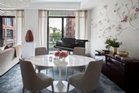 Dining table, chairs and piano in open plan living space with city view.