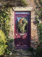 Front door of rustic cottage featuring Christmas wreath