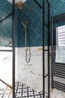 Shower enclosure with crittall style doors, brass shower head, marble tiles and teal tiles
