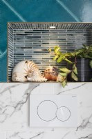 Detail of recessed lighting in shower niche and toilet flush plate tiled mix; mosaic, marble and teal tiles