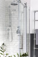 Detail of classic glass shower enclosure with marble tiles and chrome rain showered
