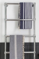 Detail of chrome towel radiator, grey panelling and hamman towels