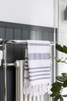 Detail of chrome heated towel radiator with grey panelling