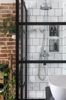 Shower with black crittall style doors, white square tiles and chrome shower head.
