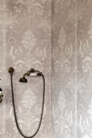 Shower detail, pink patterned tiles and brass shower