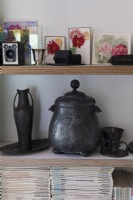 Decorative pewter items on shelves, floral paintings