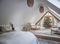 Open plan loft bedroom in neutral tones featuring seating and Christmas tree