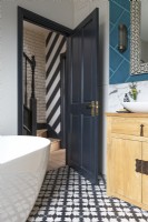 View to hallway from striking bathroom with bold tiles and Moroccan accents