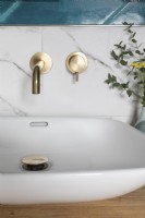 Detail of bowl sink and brass taps with marble and teal coloured tiles