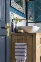 Detail of vanity unit and bowl sink with bold tiles and brass taps