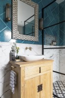 Detail of wooden vanity and sink with brass taps, Moroccan style mirror and bold tiles.