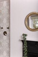 Pink bathroom detail with gilt mirror above fireplace 