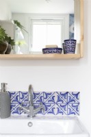 Detail of tiles and chrome mixer taps. Spanish tiles in blue and white.

