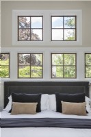 Close up of bed placed in front of multiple paned windows with garden view.