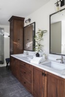 Modern bathroom with double sinks and brown wooden cabinets.