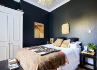 Bedroom with fabrics in neutral tones set against black walls.