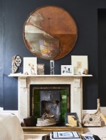 Cream marble fireplace against dark painted walls.