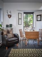 Mid century room featuring retro rug, leather armchair and wooden dining table