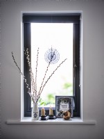 Dried flower arrangement and candles next to window