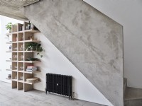 Black radiator and contemporary shelving under concrete stairway