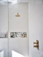 White bathroom with gold shower head and faucets