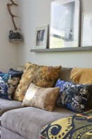 Designer cushions on a suede sofa .