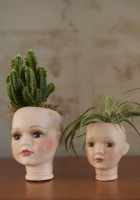 Detail of two dolls heads used as flower pots.