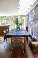 A dining table with a designer blue patterned table cloth next to a designer wallpaper feature wall.