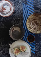 Above view of a collection of pots on a designer patterned table cloth.  
