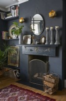 A fireplace on a dark grey wall with a collection of ornament on the mantlepiece. 