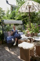 Owner sitting on her garden swing chair at her garden table. 