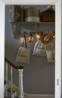 View to hallway trough a doorway, showing wall mounted shelving and hooks in natural tones.