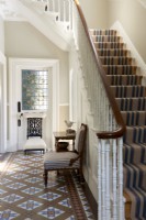 Hallways with original tiled floor and stairs with stripe runner. 