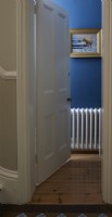 Through a door into a blue painted cloakroom showing white radiator 