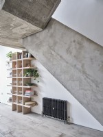 Shelving with house plants under concrete stairway