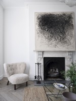 Fireplace and white armchair featuring contemporary art