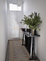 View of front door from hall featuring house plant and beige rug