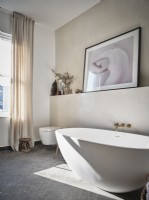 Modern bathroom featuring white bath and artwork