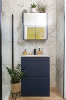 Modern sink unit and mirror in bathroom  with marble wall tiles