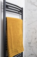 Detail of black towel radiator with mustard yellow towel