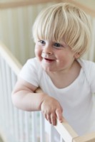 Smiling child baby boy in cot in nursery bedroom