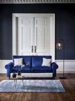 Modern blue sofa in a blue room with rug and floor lamp