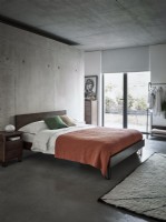 Orange bed against industrial concrete wall