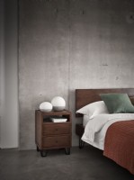Orange bed and side table against industrial concrete wall
